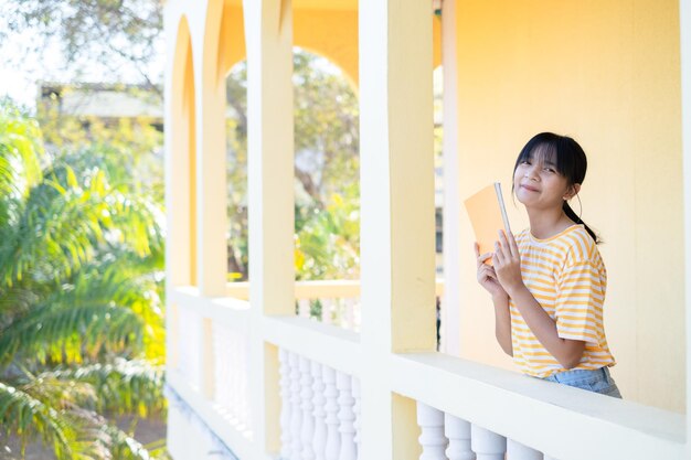 Heureuse jeune fille debout au bâtiment fond jaune