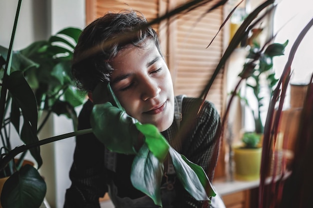 Heureuse jeune fille entourée de plantes sur le balcon environnement vert dans la chambre jardinage à la maison