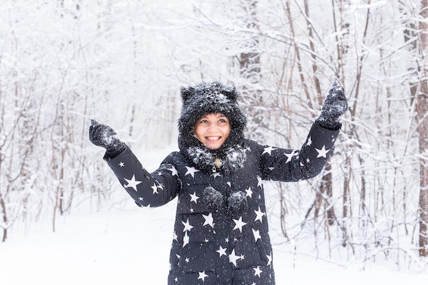 Heureuse jeune fille jette une neige dans une forêt d'hiver