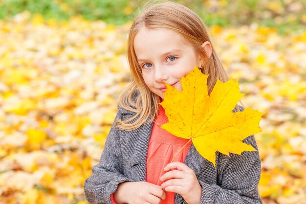 Heureuse jeune fille jouant avec la chute des feuilles jaunes