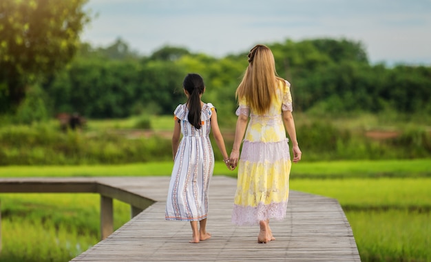 Heureuse jeune fille marchant avec sa mère sur un pont en bois