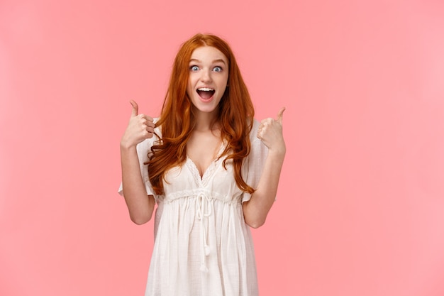 heureuse jeune fille rousse avec les pouces vers le haut