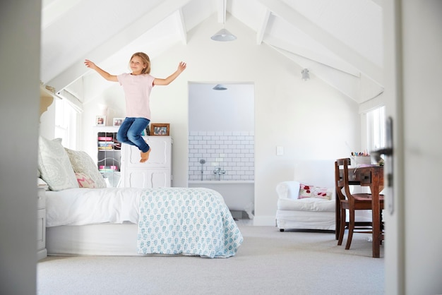 Heureuse jeune fille sautant sur le lit dans sa chambre