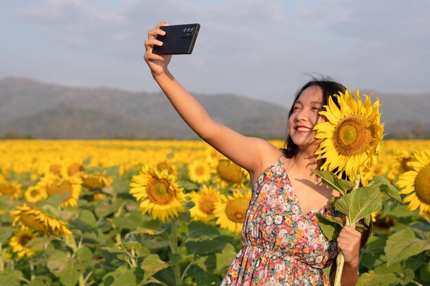 Heureuse jeune fille selfie avec tournesol au beau champ de fleurs