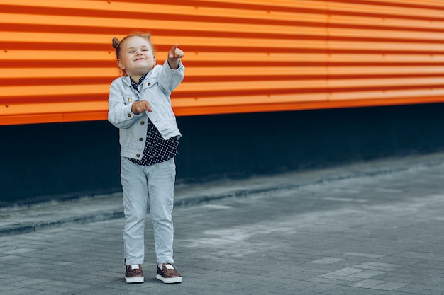 Heureuse jeune fille souriante en jeans pointant avec ses doigts