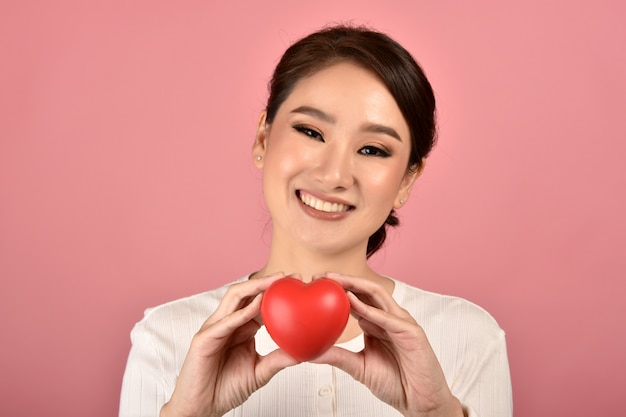 Heureuse jeune fille souriante, montrant le signe de l'amour