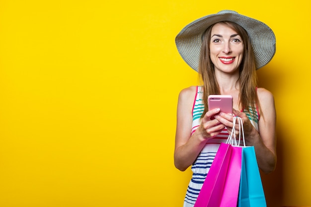 Heureuse jeune fille avec un téléphone tenant des paquets avec des achats