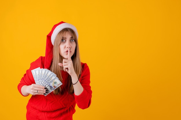 Heureuse jeune fille tenant des billets de cent dollars portant un bonnet de Noel