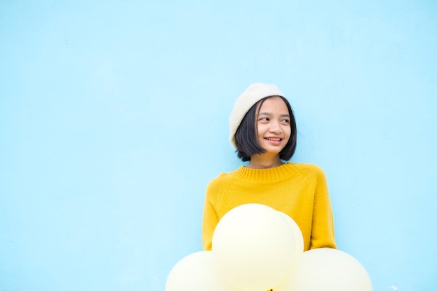 Heureuse Jeune Fille Tenir Le Ballon Jaune Porter Le Sourire De Chandail Jaune Sur Fond Bleu.