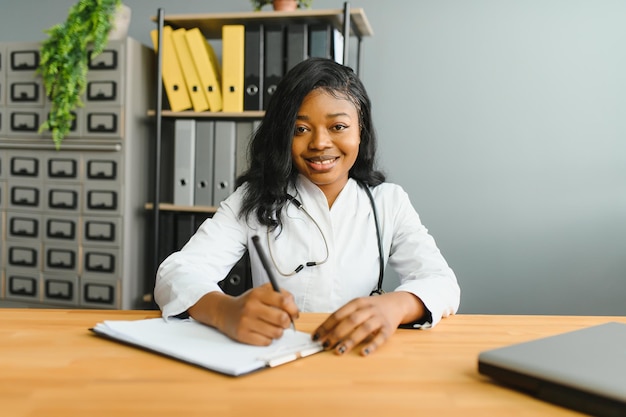 Heureuse jeune infirmière africaine travaillant au bureau