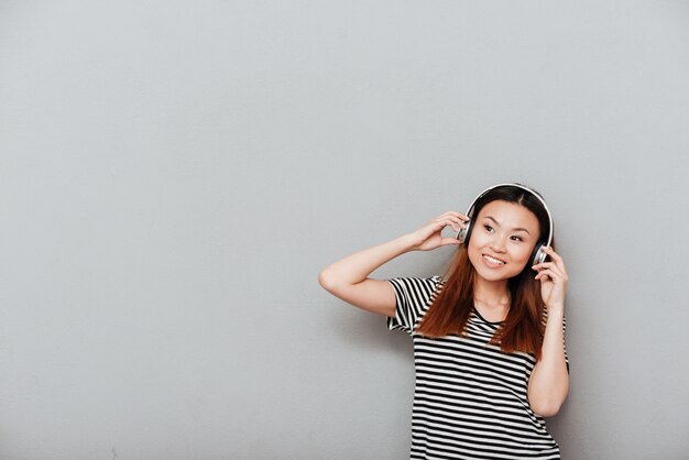 Heureuse jeune jolie femme écoutant de la musique avec des écouteurs