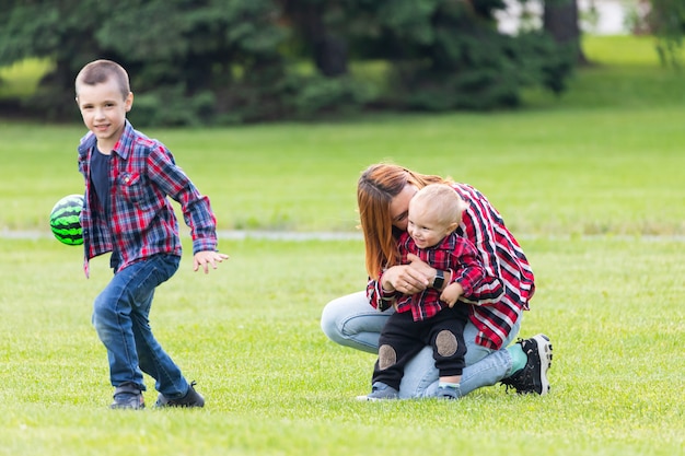 Heureuse jeune maman joue avec le ballon avec son bébé dans un parc sur une pelouse verte