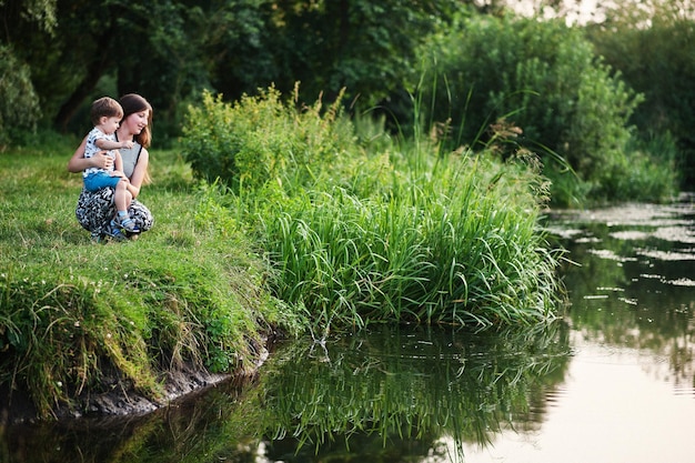 Heureuse jeune mère de famille avec enfants fils sur la nature s'amusant