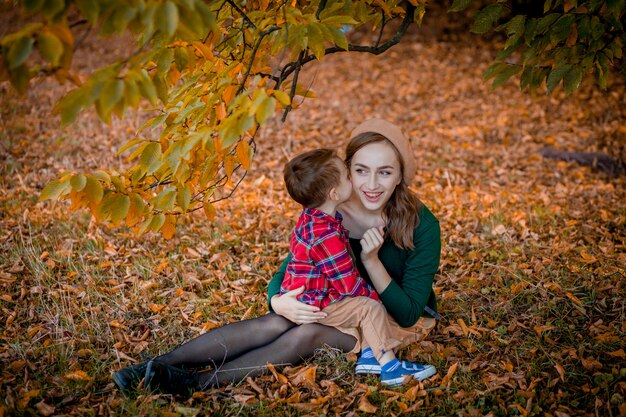 Heureuse jeune mère jouant et s'amusant avec son petit bébé sur la chaude journée d'automne ensoleillée dans le parc. Concept de famille heureuse.