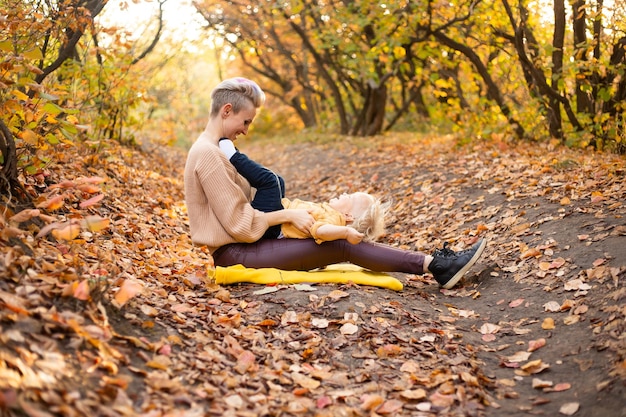 Heureuse jeune mère jouant avec son petit bébé au soleil d'automne chaud