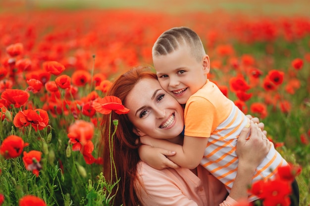 Heureuse jeune mère riante avec son fils sur fond de champ de coquelicots