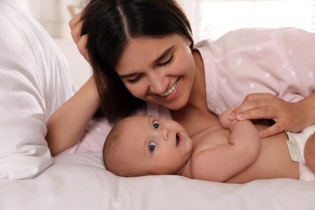 Heureuse jeune mère avec son bébé mignon sur le lit à la maison