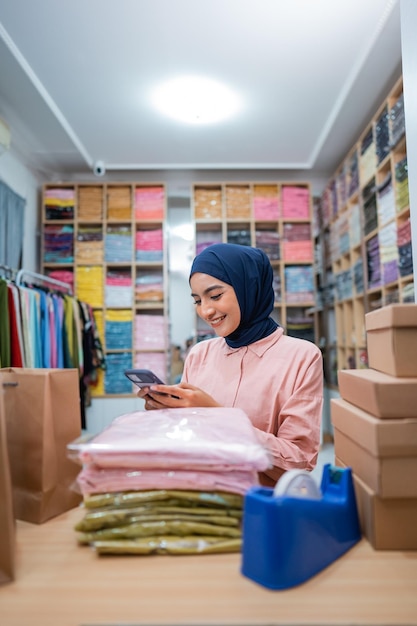 Heureuse jeune vendeuse utilisant un téléphone assis sur un bureau