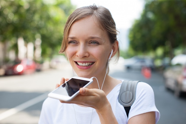 Heureuse jolie femme ayant un appel audio à l&#39;extérieur