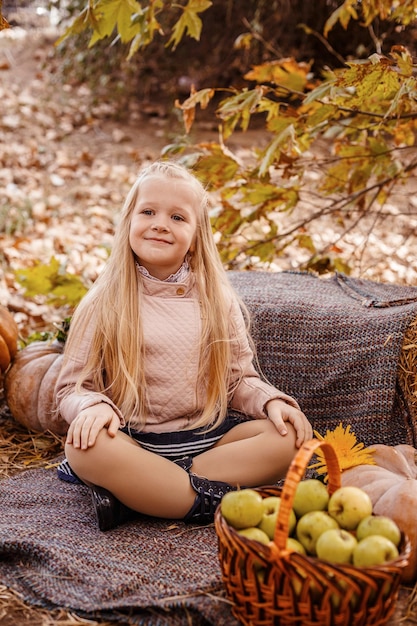 Heureuse jolie fille en automne automne en plein air Célébrer le festival de la récolte Enfant fille récolte de légumes frais style rustique Enfant présentant la récolte potager fond en bois Vacances de récolte d'automne