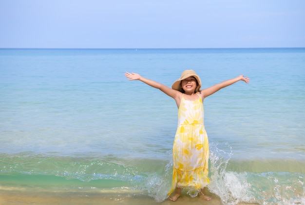 Heureuse jolie fille jouant sur la plage,