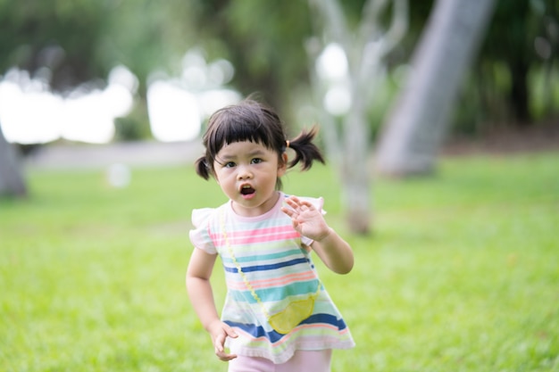 Heureuse jolie fille souriante et courant dans le jardin