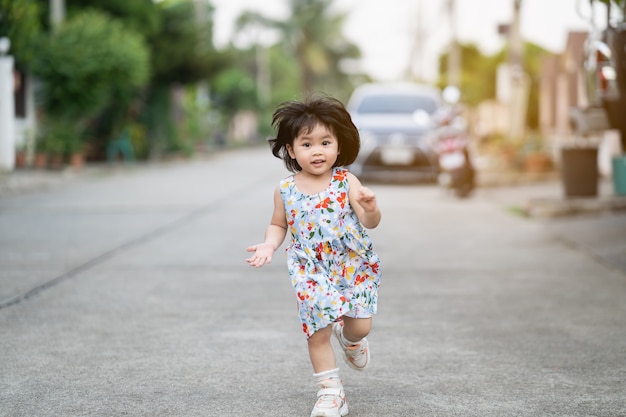 Heureuse jolie fille souriante et courant sur la route