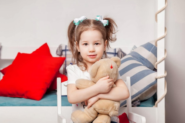 Heureuse jolie fille de trois ans assise avec un ours en peluche