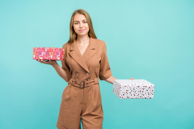 Heureuse jolie jeune femme tenant une boîte-cadeau sur fond bleu.