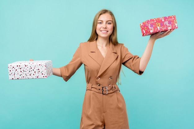 Heureuse jolie jeune femme tenant une boîte-cadeau sur fond bleu.