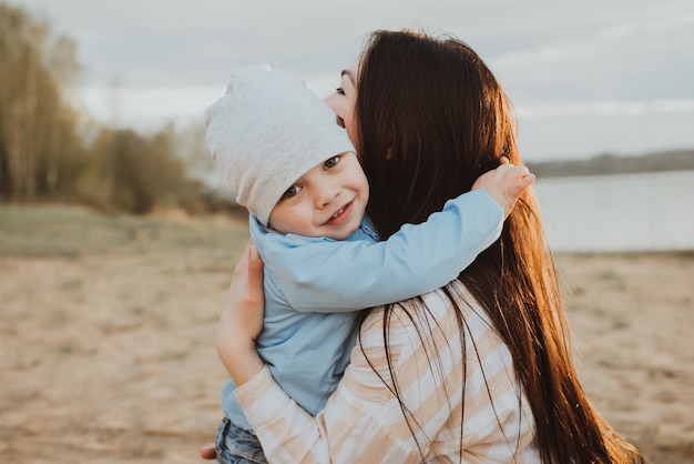 Heureuse maman embrasse son fils sur la plage en été dans la nature