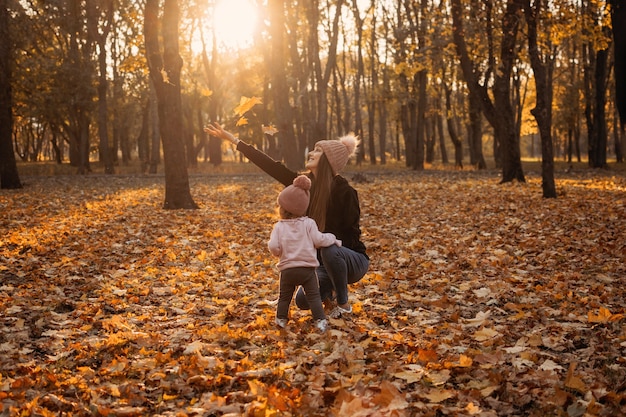 Heureuse maman de famille et petite fille jouant à l'extérieur dans le parc d'automne petite fille et sa mère dans le