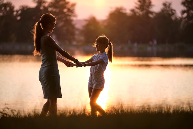 Heureuse maman et fille fille se détendre main dans la main en profitant du temps ensemble dans le parc d'été au coucher du soleil Concept d'amour et de relation familiale