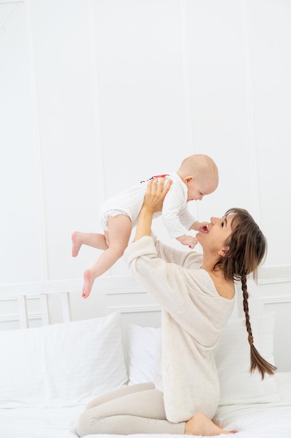 Heureuse maman avec une petite fille à la maison sur le lit câlins et bisous heureuse jeune mère et maternité