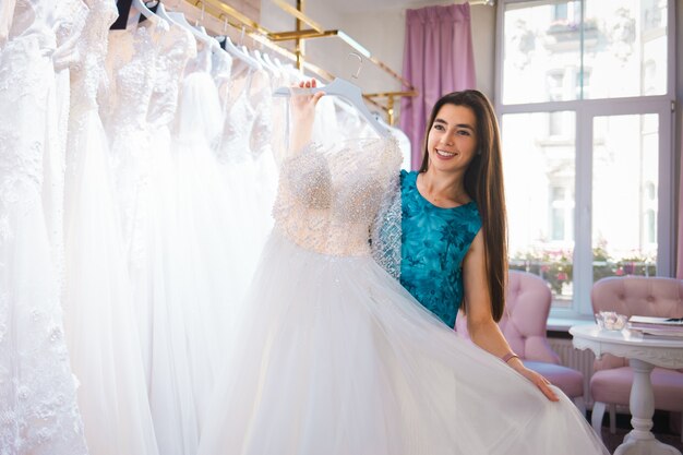 Heureuse mariée choisit une robe dans une boutique de mariage