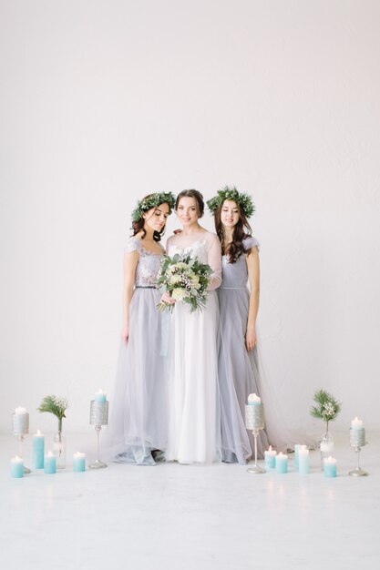 Heureuse mariée dans une robe blanche détient un bouquet de mariée et se tient avec ses demoiselles d'honneur en robes grises