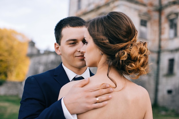 Heureuse mariée et le marié au jour du mariage marchant à l'extérieur sur le territoire du château