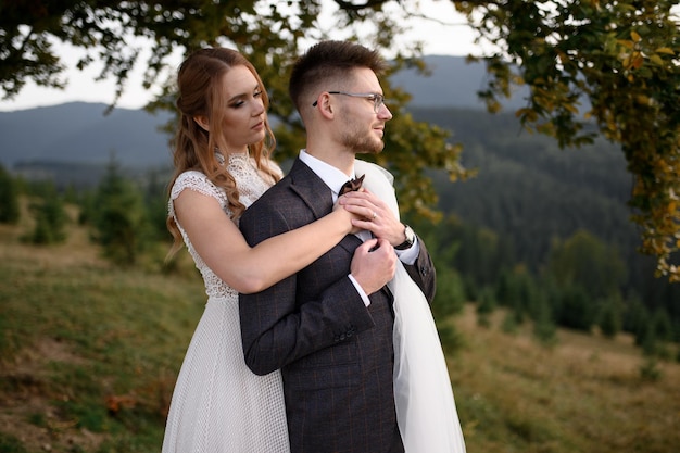 Heureuse mariée et le marié élégants courant et s'amusant dans les montagnes par une journée ensoleillée d'été