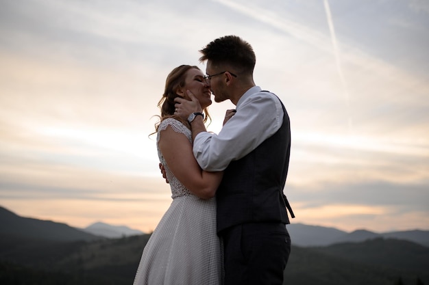 Heureuse mariée et le marié élégants courant et s'amusant dans les montagnes par une journée ensoleillée d'été