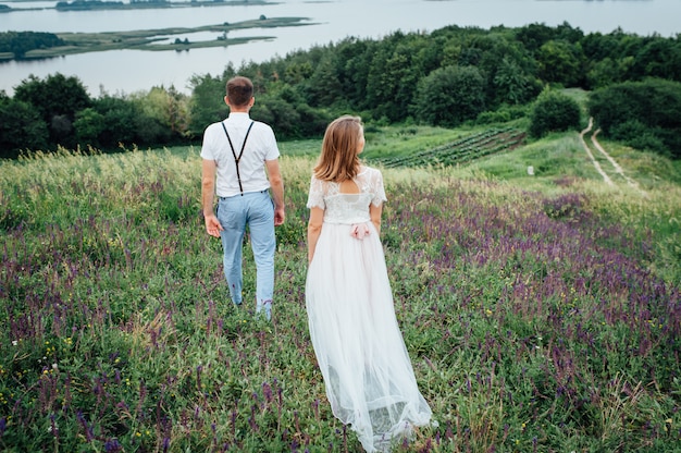 Heureuse mariée et le marié marchant sur l'herbe verte