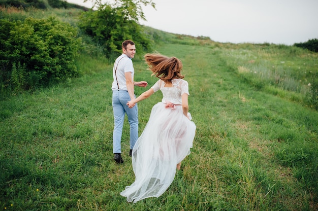 Heureuse mariée et le marié marchant sur l'herbe verte