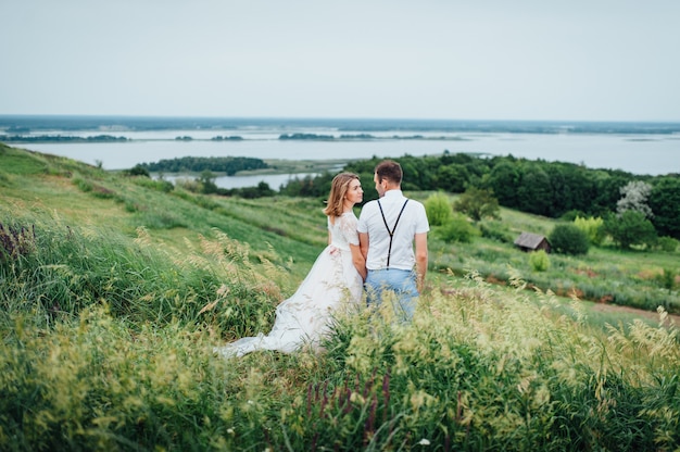 Heureuse mariée et le marié marchant sur l'herbe verte