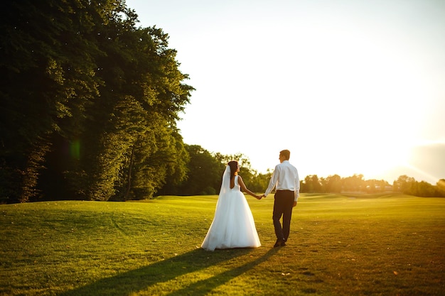 Heureuse mariée et le marié vont au coucher du soleil Beau couple de mariage au coucher du soleil