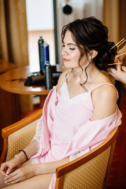 Heureuse mariée avec un sourire faisant ses cheveux