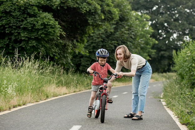 Heureuse mère apprend à son enfant à faire du vélo sur la piste cyclable