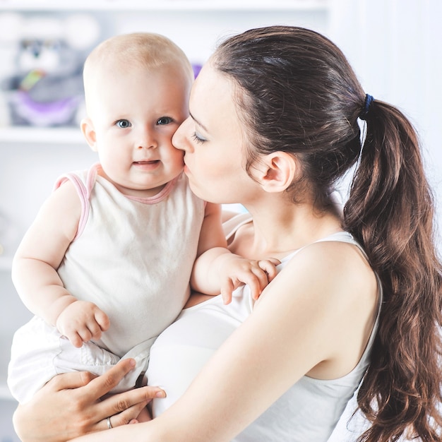 Heureuse mère avec un bébé d'un an dans ses bras de la chambre d'un enfant.la photo a un espace vide pour votre texte