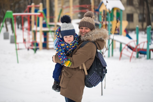 heureuse mère et bébé dans le parc d'hiver. famille à l'extérieur. maman joyeuse avec son enfant