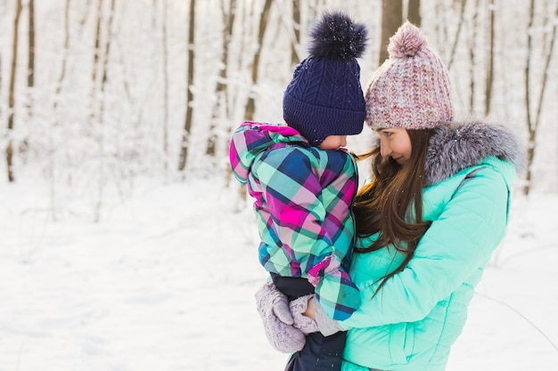 Heureuse mère et bébé dans le parc d'hiver. famille à l'extérieur. maman joyeuse avec son enfant.