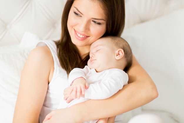 Heureuse mère avec bébé sur le lit