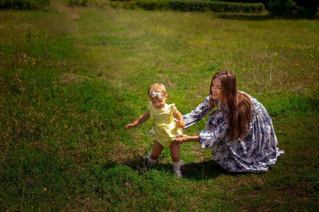 Heureuse mère élégante joue avec sa petite fille dans le jardin verdoyant